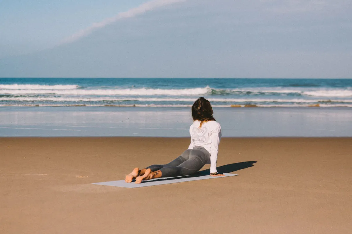 Frau auf Yogamatte am Strand